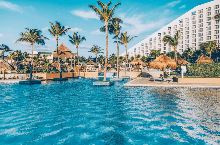 the pool area at Iberostar Selection Cancun with palm trees and the accommodation as a backdrop 