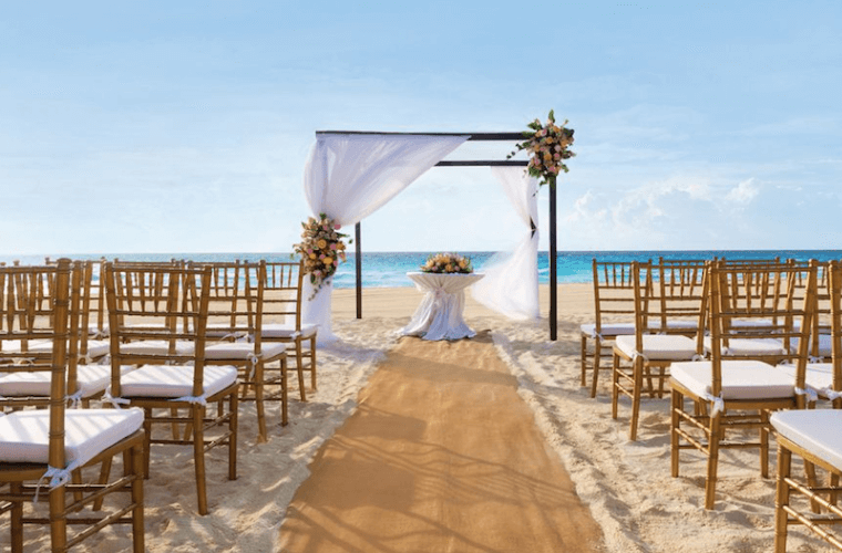 beach wedding setup at Wyndham Alltra Cancun with a wedding arch and the Caribbean Sea in the background 