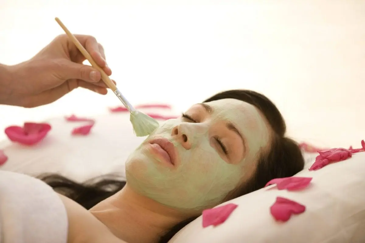 Person getting a facial while laying down on flower peddles