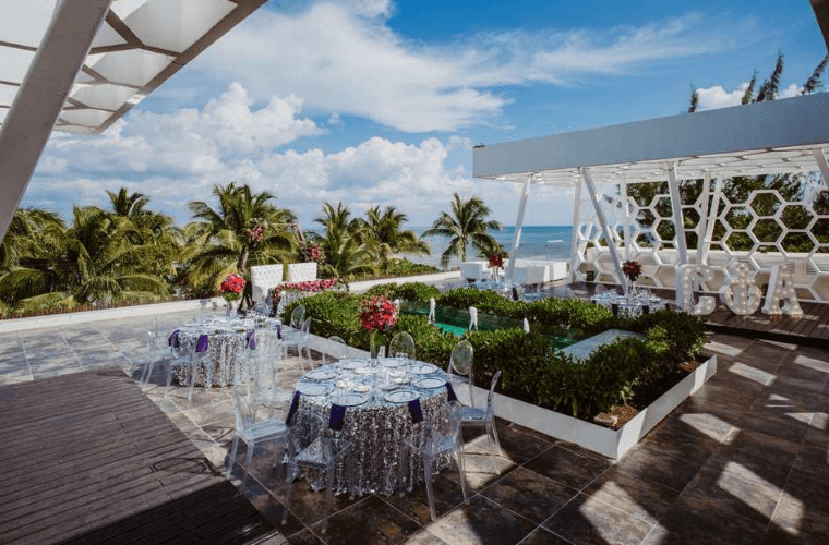 terrace wedding space with white tables at Sandos Caracol