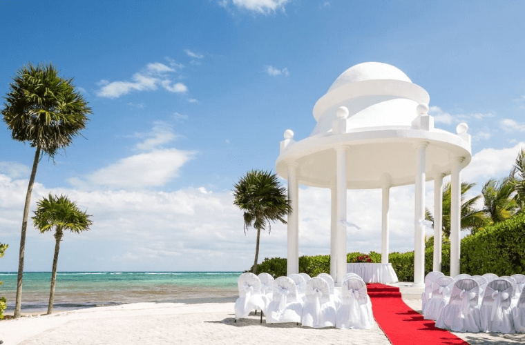 beach wedding gazebo with a white covered altar table and white chairs around it