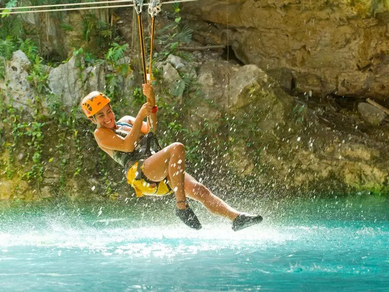 Woman zip lining into the water at Xplor Park Cancun