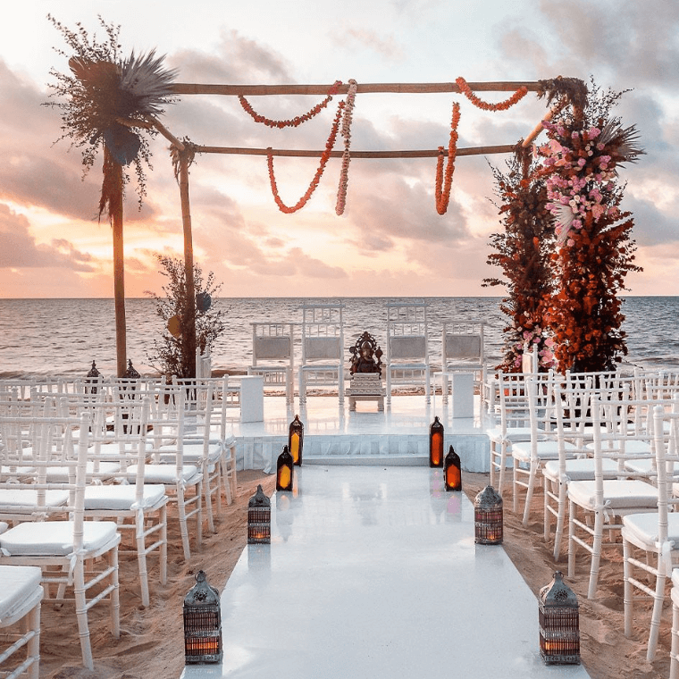 wedding venue at Moon Palace Cancun with an arch, white chairs, and views of the Caribbean Sea in the background 