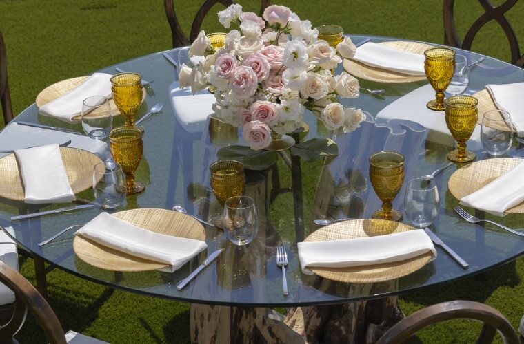 a round table set for a wedding reception with pink roses in the center of the table 