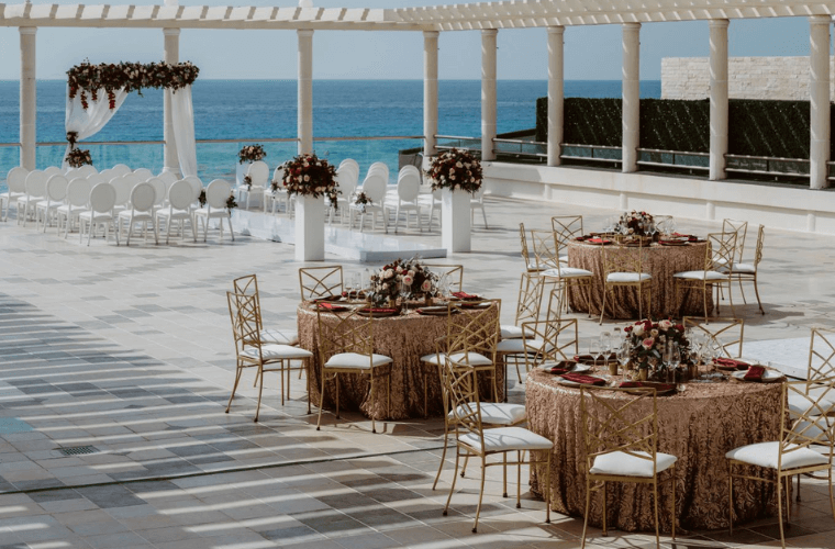 wedding setup at Terrace Martiniere with a wedding arch, white chairs, and round tables set for the reception 