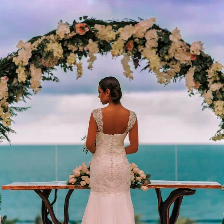 a bride under a flower arch looking out across the Caribbean Sea 