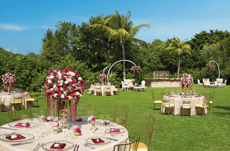 garden wedding venue at Dreams Tulum with tables set with red and white flowers 