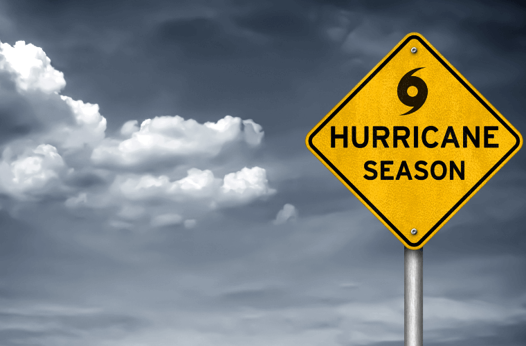 a yellow sign saying hurricane season with dark clouds in the background 
