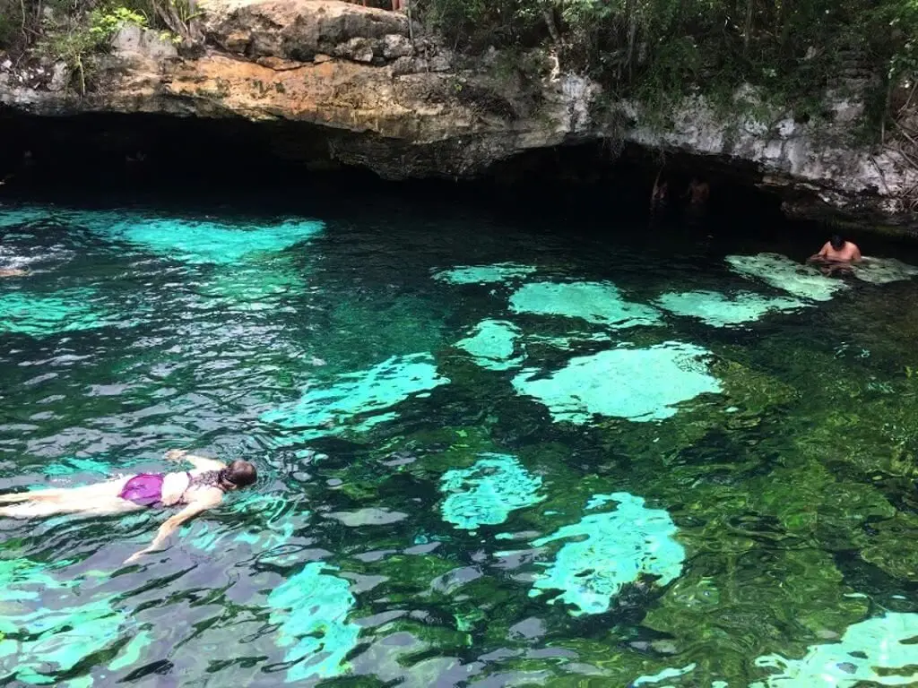 People swimming in blue cenote