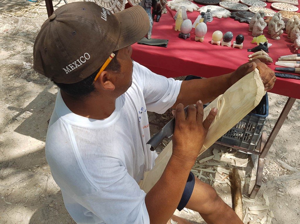 A local resident carves a wooden mask