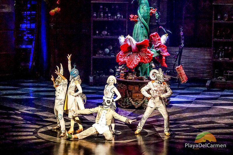 Cirque Du Soleil actors pose in front of a gian plant 