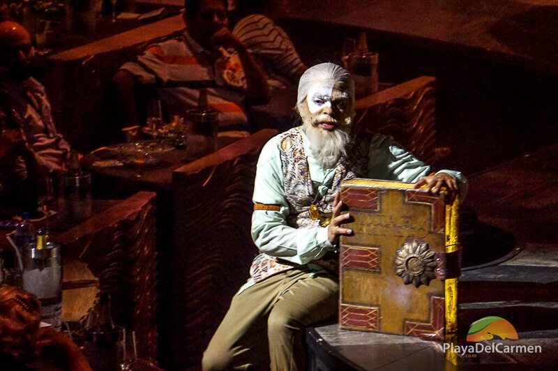 An actor sitting on stage with a book at Cirque Du Soleil theater in the Riviera Maya