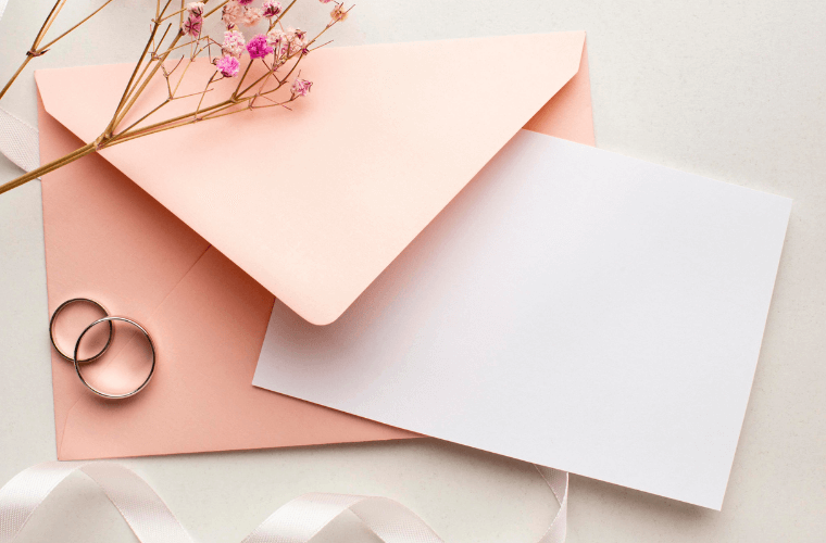 pink and white wedding stationery and two wedding rings 