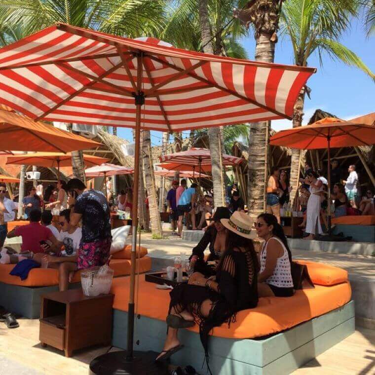 people seated under a shade at a beach club 