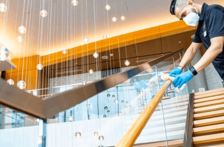 a man wearing a mask cleaning a balustrade 