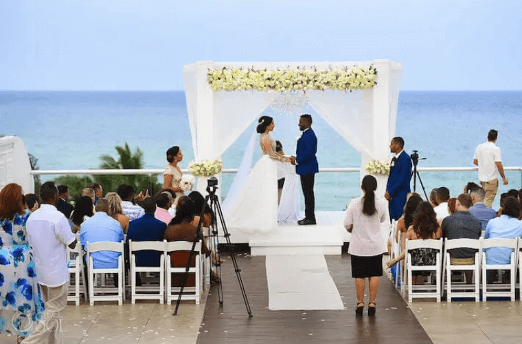 a wedding couple getting married on the beach in front of their wedding guests