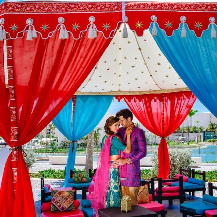 an Indian couple surrounded by colorful decor at Grand Palladium