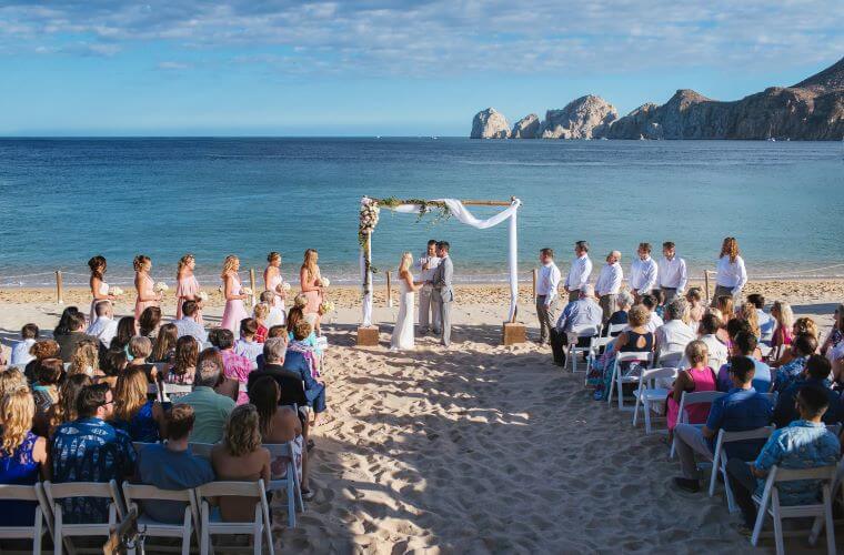 a couple marrying on the beach with their guests looking on