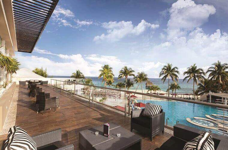 the balcony area, pool, and beach at Fives Beach 