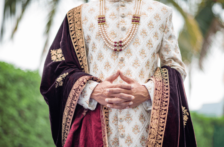 the torso of a groom in elaborate wedding clothing 