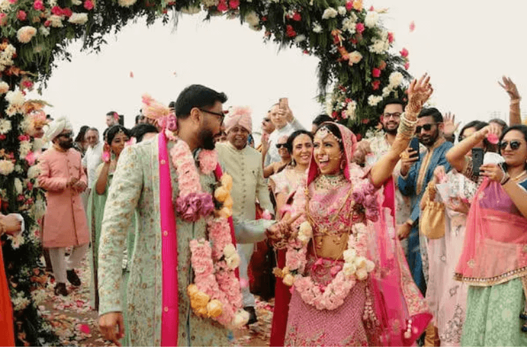 an Indian wedding couple with their guests dressed in bright clothing 