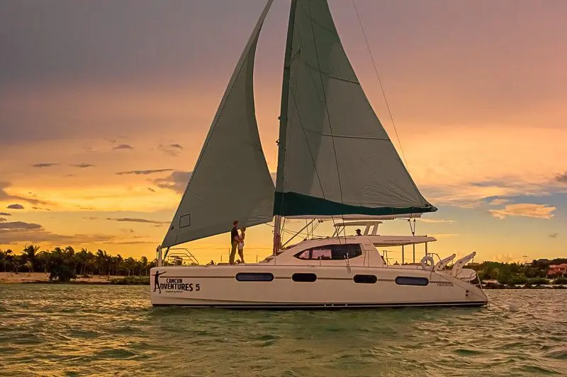 A catamaran sailing at sunset along the Riviera Maya coastline