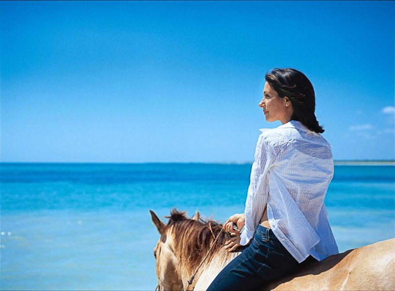 Woman on a horse at the beach in Riviera Maya, Mexico looking out at the Caribbean Sea