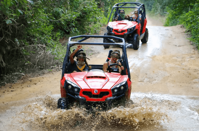 two buggies being driven through the jungle one behind the other 