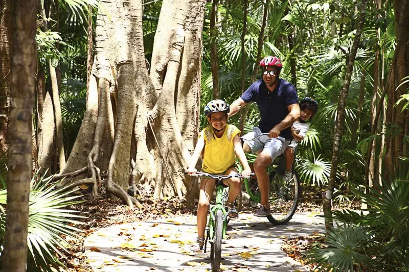 A father and daughter ride bikes at Sandos Caracol, Playa del Carmen