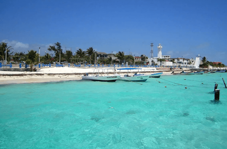 boats on the water at Puerto Morelos with sand and palm trees in the background 