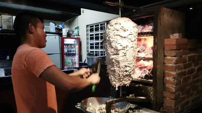 Guy cutting slow cooked meat for taco