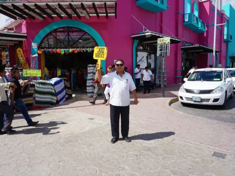 A taxi driver stands in front of a taxi stand in Playa del Carmen