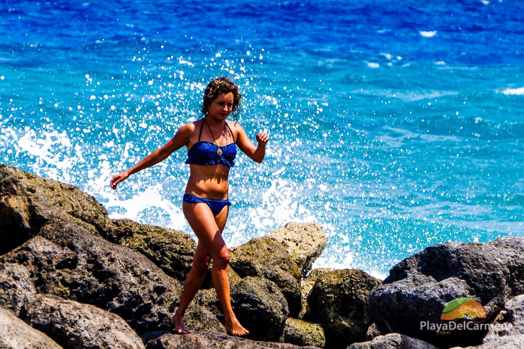 A woman walks along the rocks in Puerto Aventuras