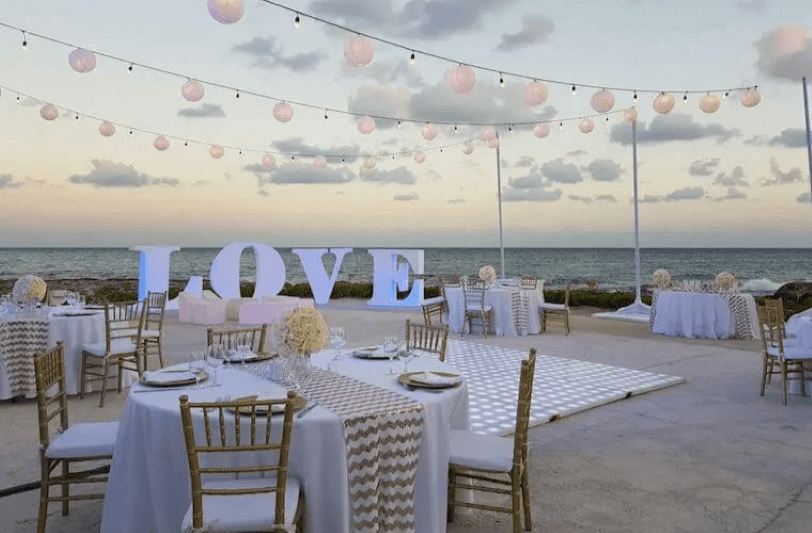 a beach wedding venue set with chairs, tables, and a freestanding love sign