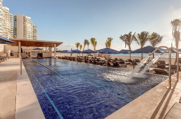 the pool area with palm trees in the background at Royalton Chic Cancun 