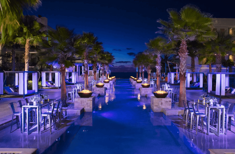 wedding cocktails setup at Breathless Riviera Cancun in the evening with palm trees and real flames