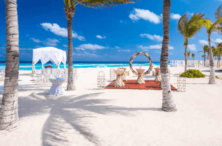 beach wedding setup at Wyndham Alltra Cancun with white sand and palm trees 