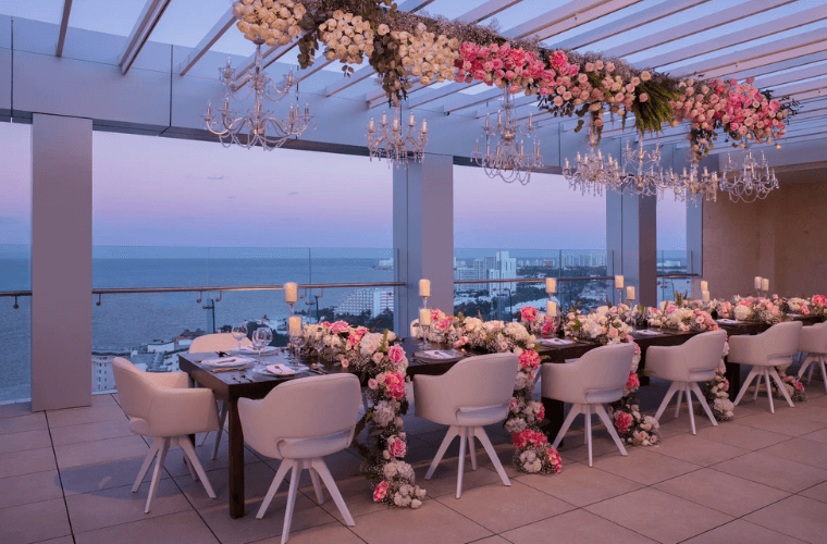 a long table decorated with pink and white flowers and candles 