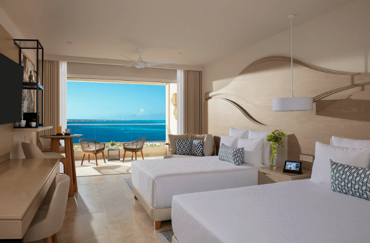 suite withy two double beds and chairs on a terrace looking out across the Caribbean Sea 