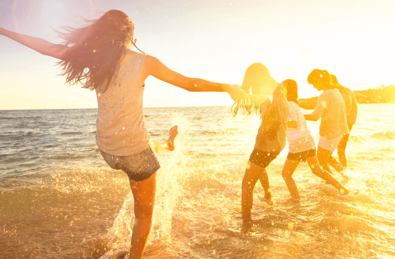 young people splashing in the water on the beach