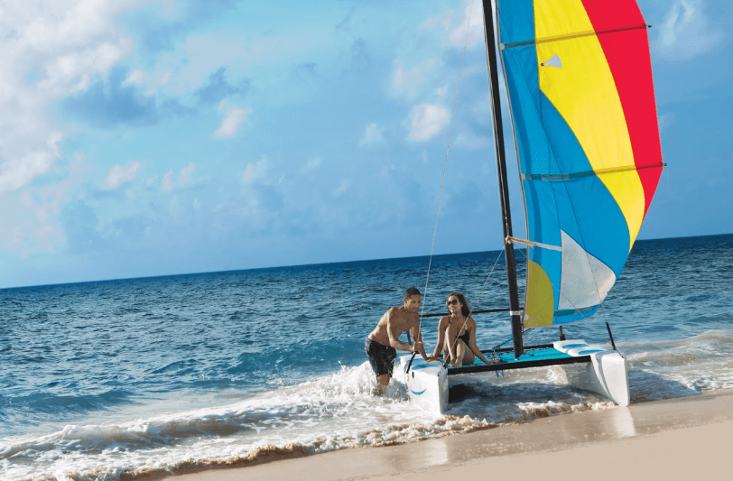 a couple with a small sail boat on the beach 