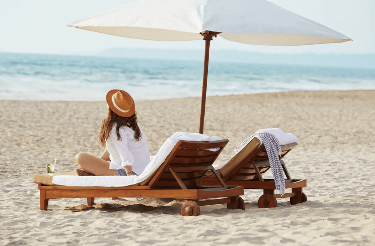 a woman relaxing on a ;lounger on the beach 