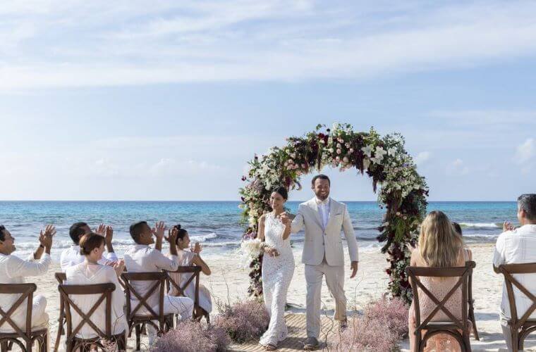 a wedding couple walking between their guests after a beach wedding ceremony