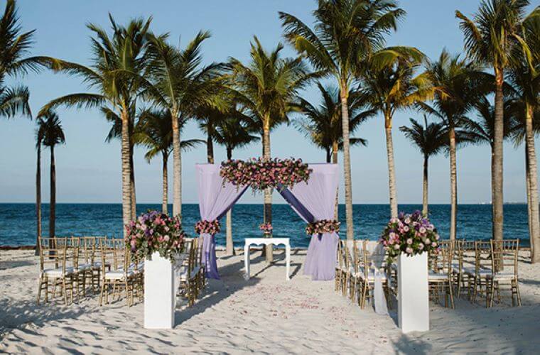 beach wedding setup at Riu Palace Costa Mujeres surrounded by palm trees 