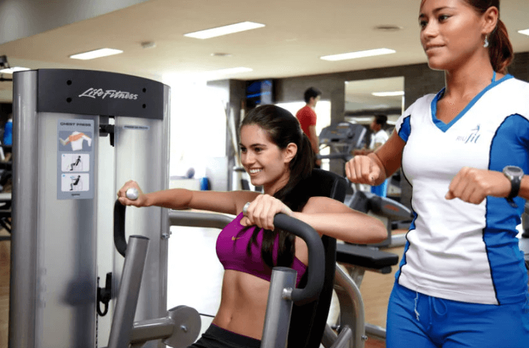 two women using fitness equipment in a gym