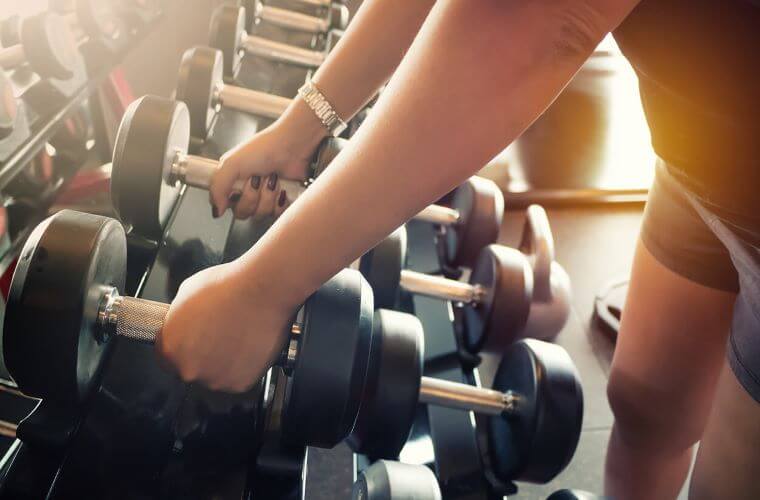 a person's arms with their hands holding weights 