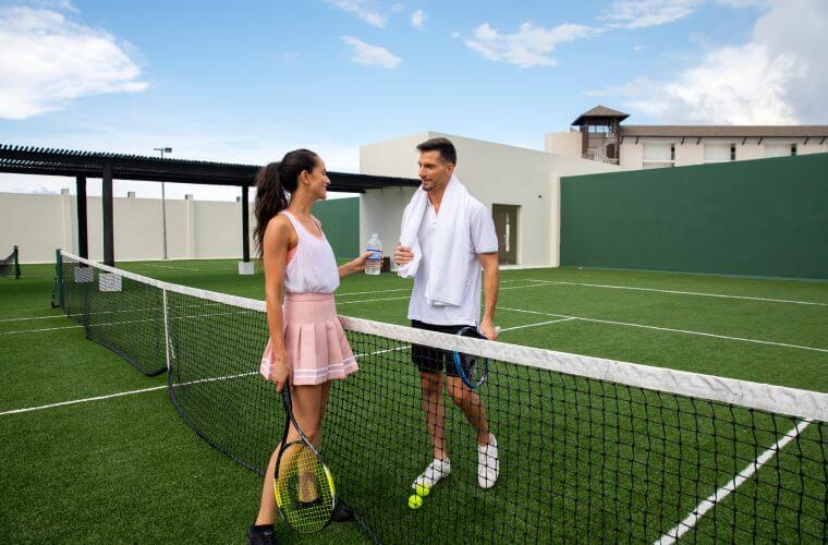 a man and woman talking across a tennis court net