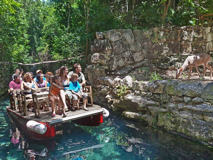 Family boating down river at Xcaret Park while looking at a deer